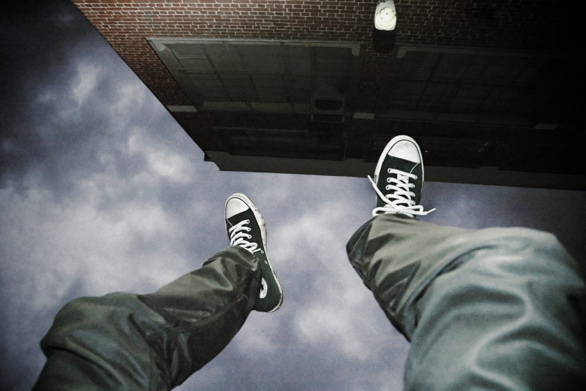 Foto suggestiva di una persona con scarpe Converse sospesa nel vuoto, simbolo di rischio e pericolo psicologico.